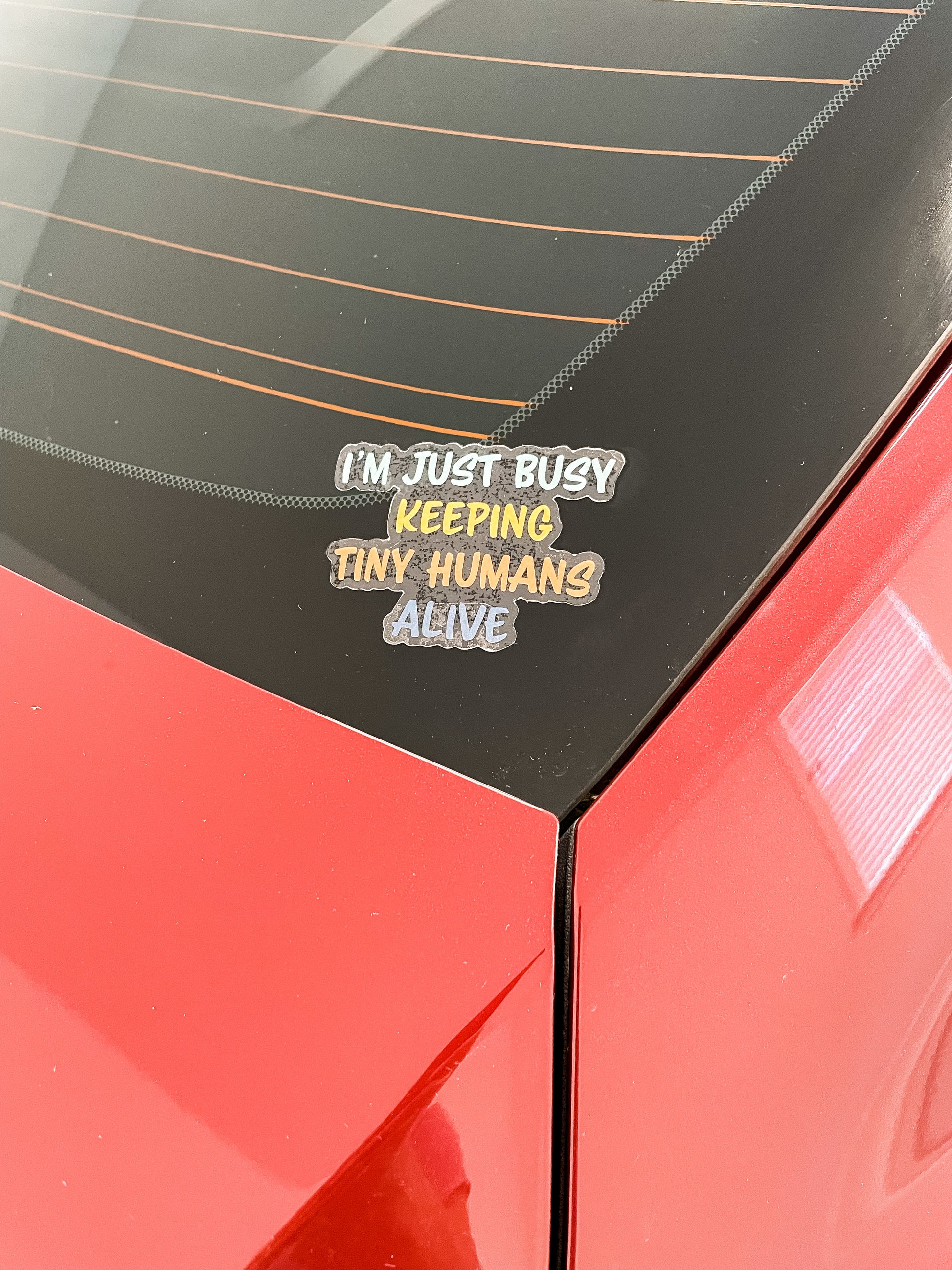 I'm just busy keeping tiny humans alive clear sticker pictured on rear car window